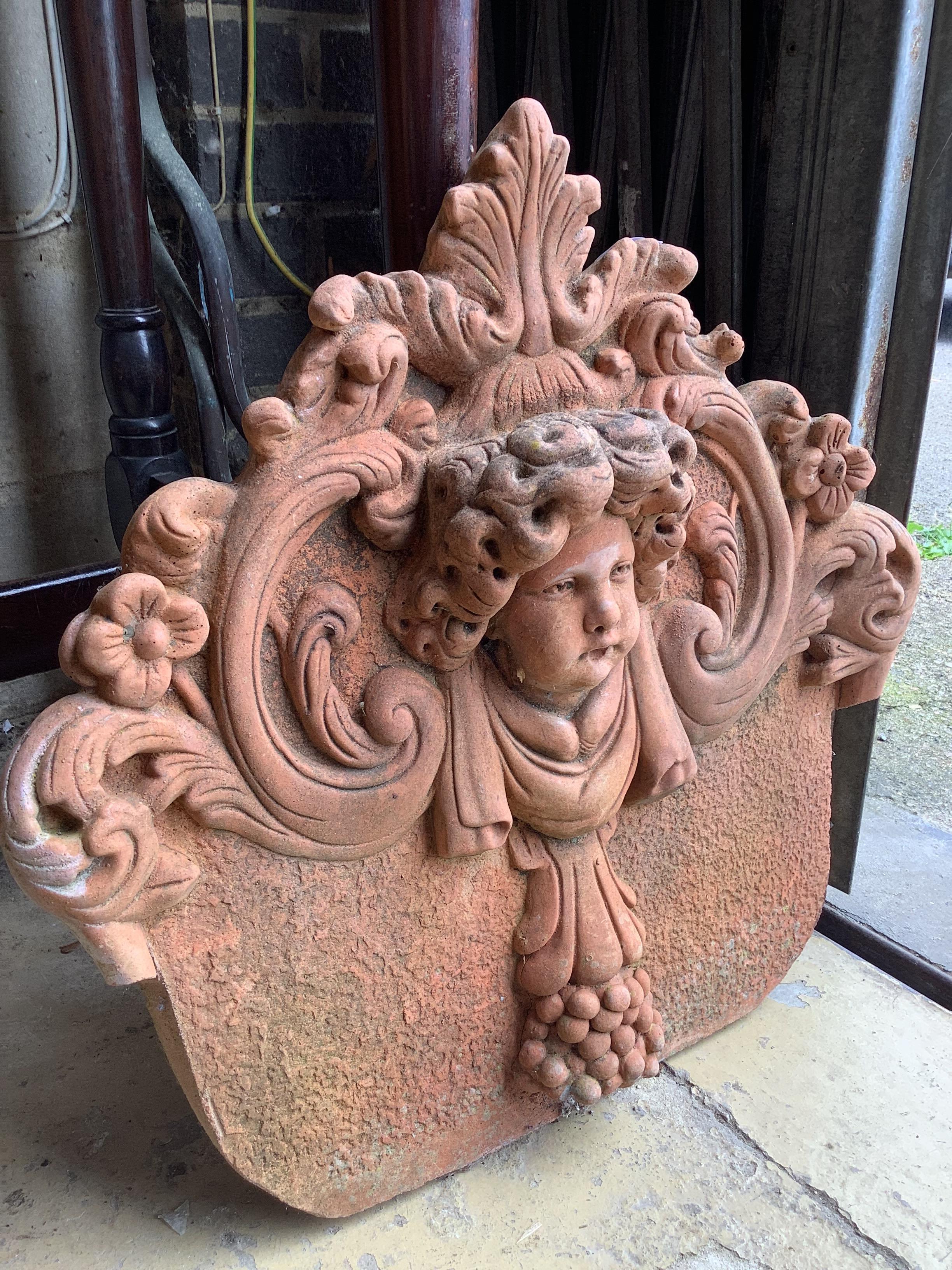 A terracotta cherub head garden wall plaque, width 54cm, height 54cm